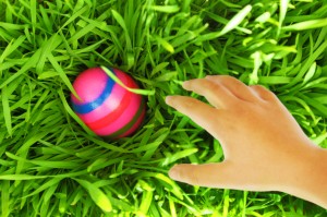 Hand reaching for Easter egg on green grass